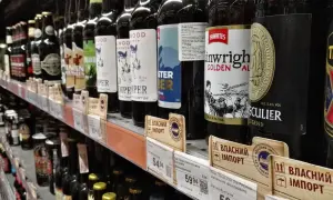 Rząd butelek piwa na półce sklepowej, niektóre z etykietami w języku ukraińskim, sugerującymi import. Widać ceny i nazwy piw, np. "Thwaites Wainwright Golden Ale".