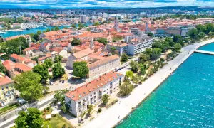 Zadar w czerwcu: słoneczna pogoda nad Adriatykiem, widok na miasto z czerwonymi dachami, promenadę i turkusowe morze.