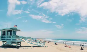 Słoneczna plaża w USA z wieżą ratowniczą i ludźmi odpoczywającymi nad oceanem. Idealne miejsce, by sprawdzić, ile trwają wakacje w USA.