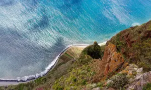 Widok z góry na klif i ocean. Tarasowe pola uprawne na zboczu, fale rozbijające się o brzeg. Madera pogoda styczeń.