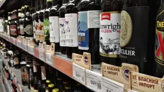 Rząd butelek piwa na półce sklepowej, niektóre z etykietami w języku ukraińskim, sugerującymi import. Widać ceny i nazwy piw, np. "Thwaites Wainwright Golden Ale".