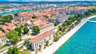 Zadar w czerwcu: słoneczna pogoda nad Adriatykiem, widok na miasto z czerwonymi dachami, promenadę i turkusowe morze.