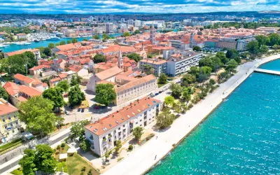 Zadar w czerwcu: słoneczna pogoda nad Adriatykiem, widok na miasto z czerwonymi dachami, promenadę i turkusowe morze.
