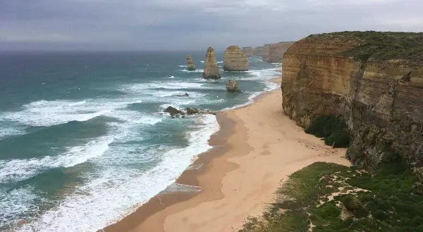 Piękne klify i plaża nad oceanem, kiedy w Australii jest lato. Woda jest turkusowa, a fale rozbijają się o brzeg.