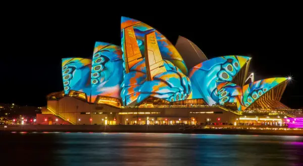 Sydney Opera House nocą, oświetlona kolorowymi projekcjami.