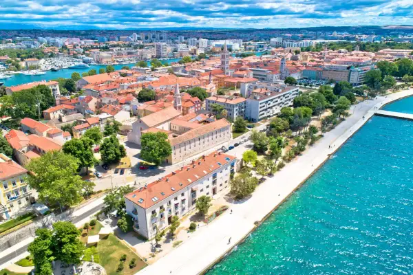 Zadar w czerwcu: słoneczna pogoda nad Adriatykiem, widok na miasto z czerwonymi dachami, promenadę i turkusowe morze.